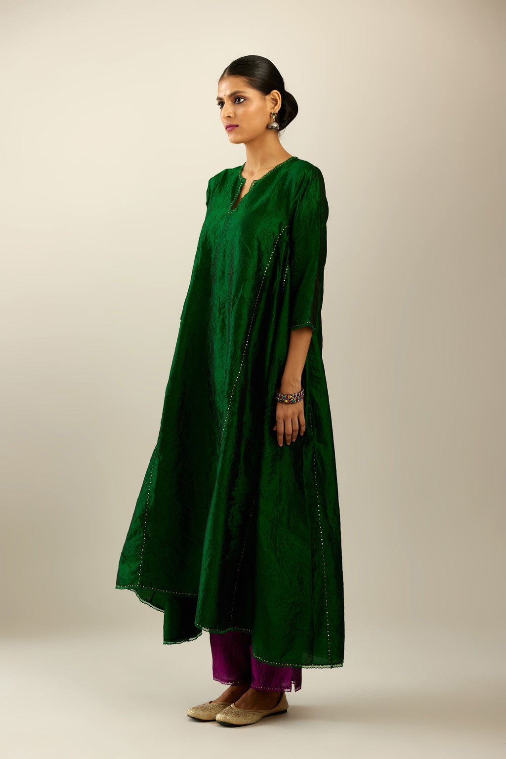Dark green hand crushed silk kurta set with asymmetric hem, highlighted with gold sequins and embroidered scalloped organza at edges.