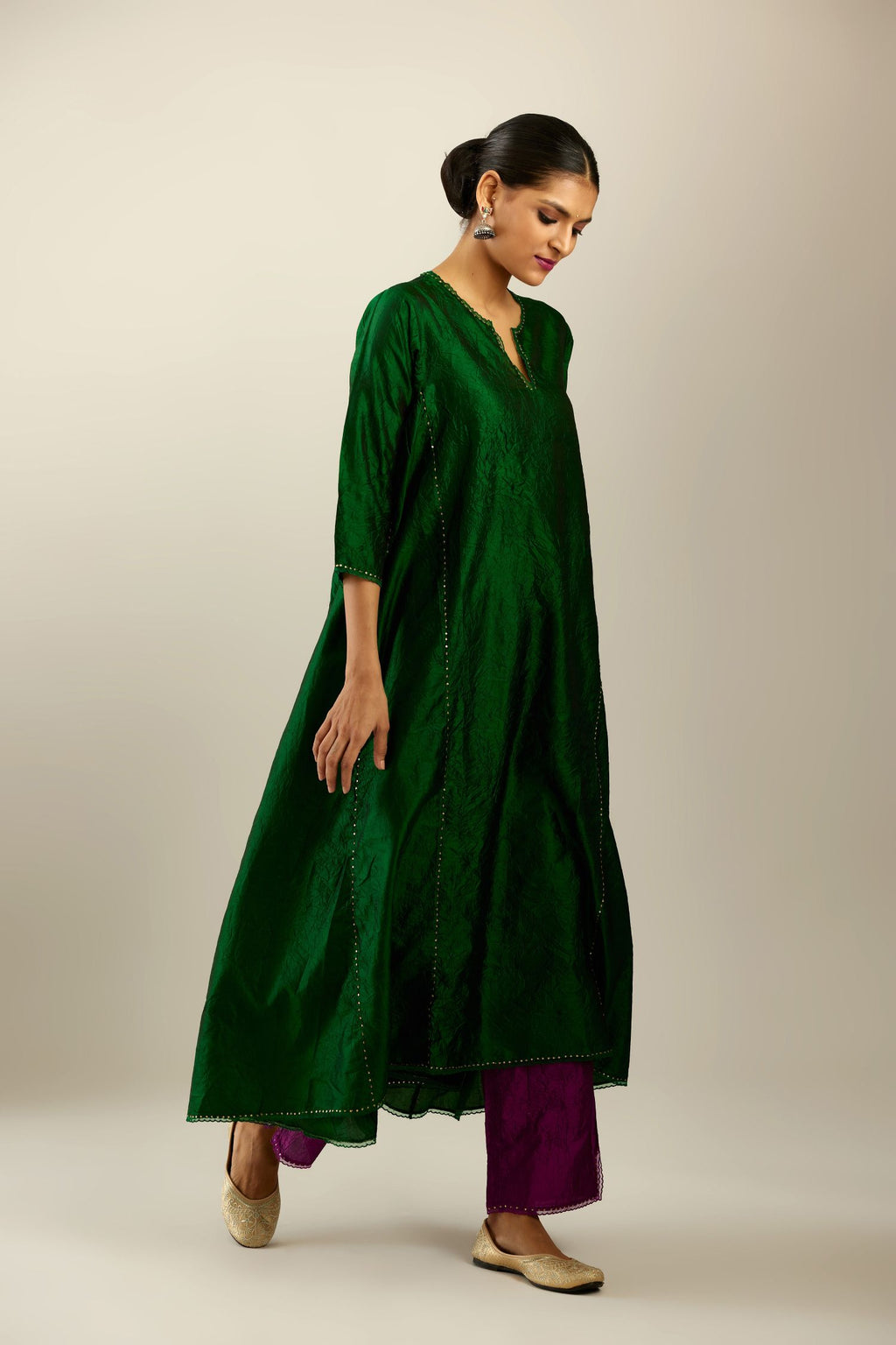 Dark green hand crushed silk kurta set with asymmetric hem, highlighted with gold sequins and embroidered scalloped organza at edges.