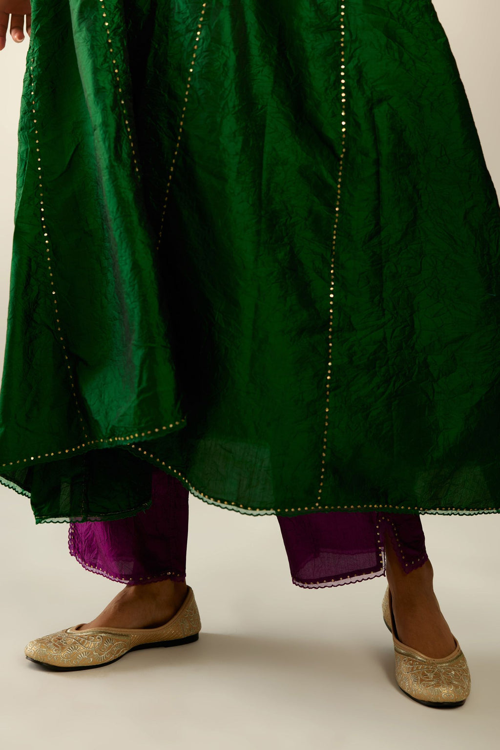 Dark green hand crushed silk kurta set with asymmetric hem, highlighted with gold sequins and embroidered scalloped organza at edges.
