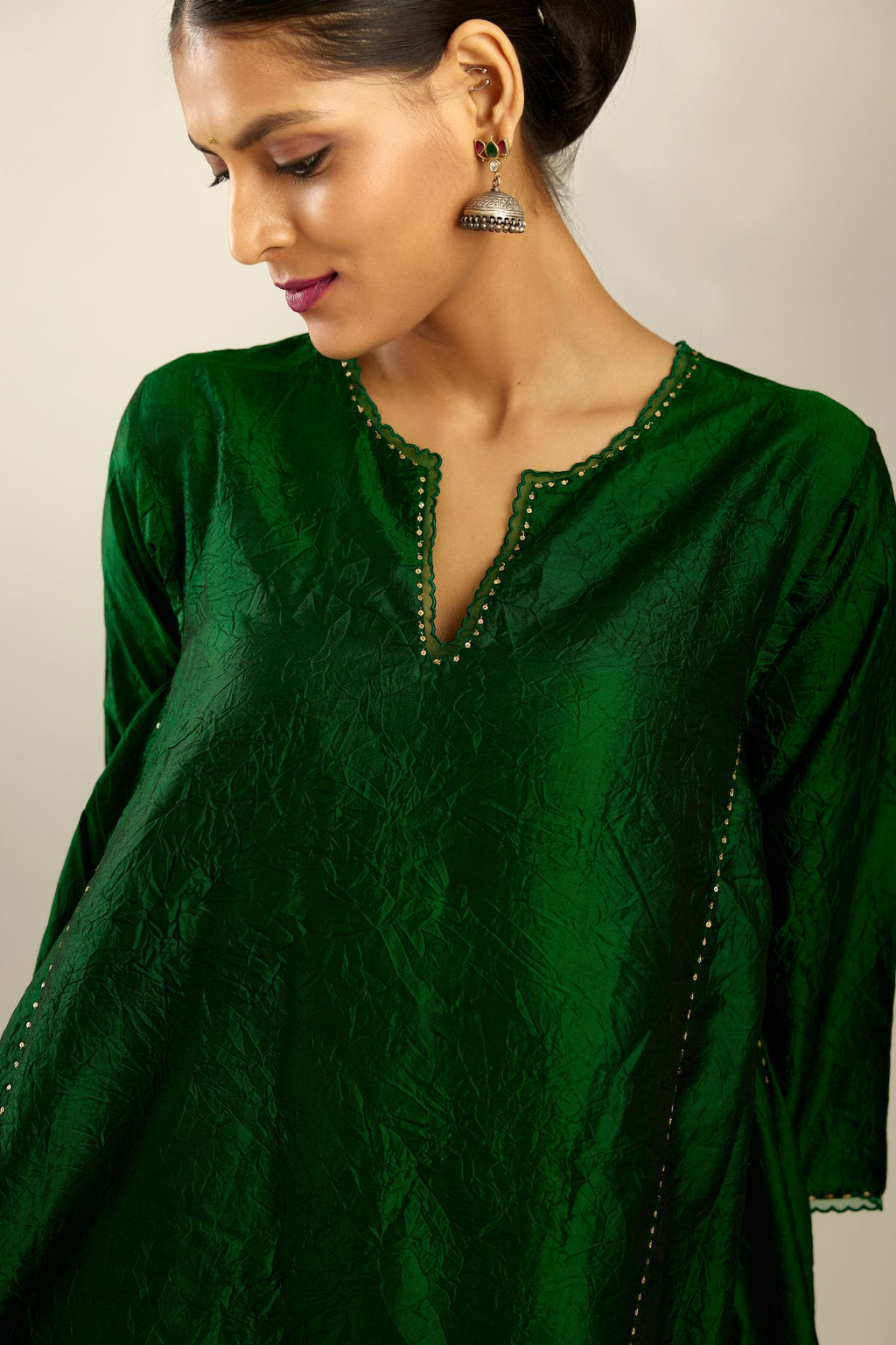 Dark green hand crushed silk kurta set with asymmetric hem, highlighted with gold sequins and embroidered scalloped organza at edges.