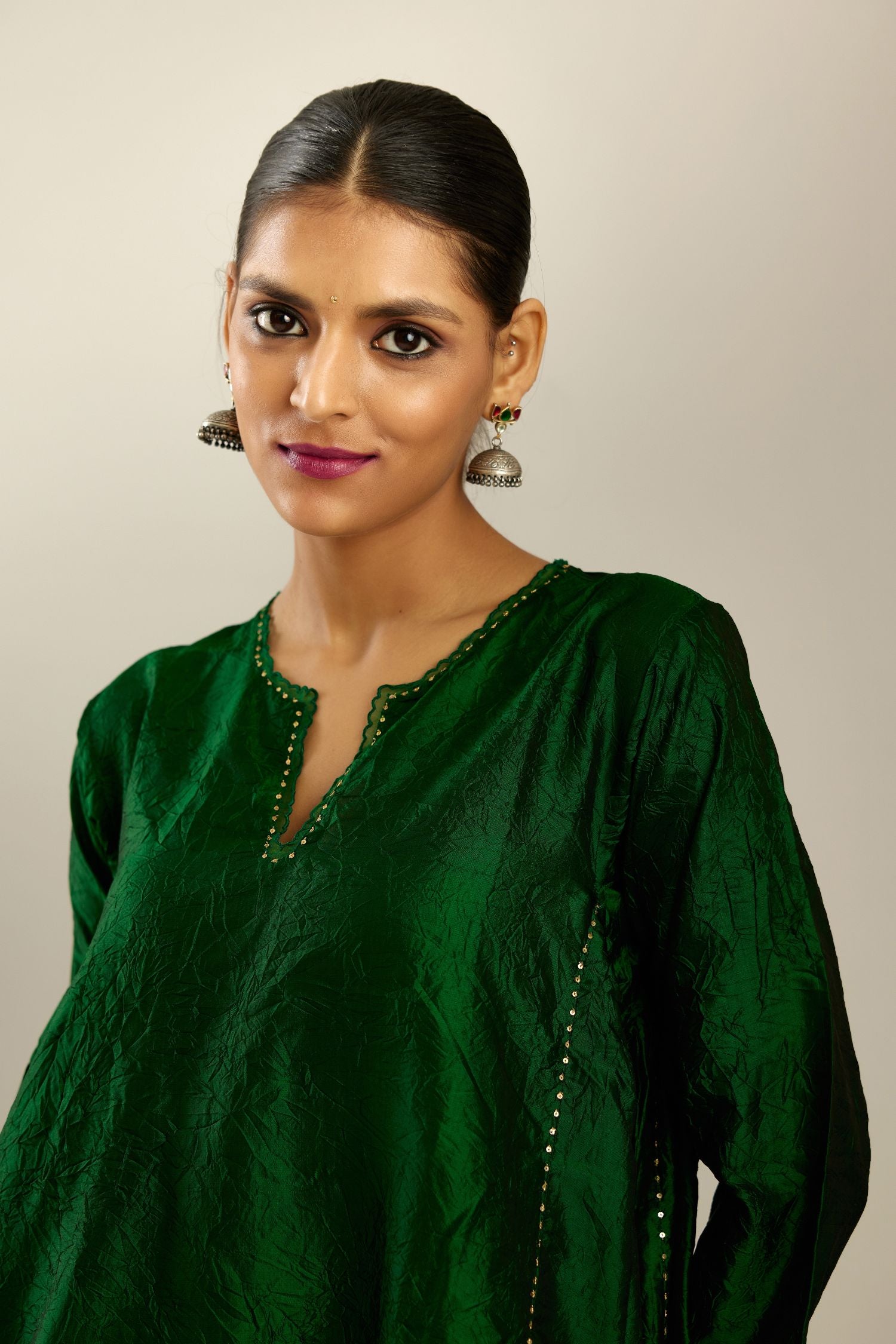 Dark green hand crushed silk kurta set with asymmetric hem, highlighted with gold sequins and embroidered scalloped organza at edges.