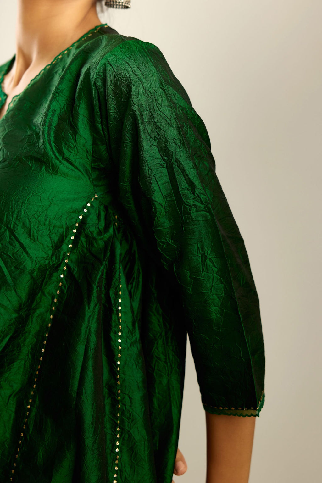 Dark green hand crushed silk kurta set with asymmetric hem, highlighted with gold sequins and embroidered scalloped organza at edges.