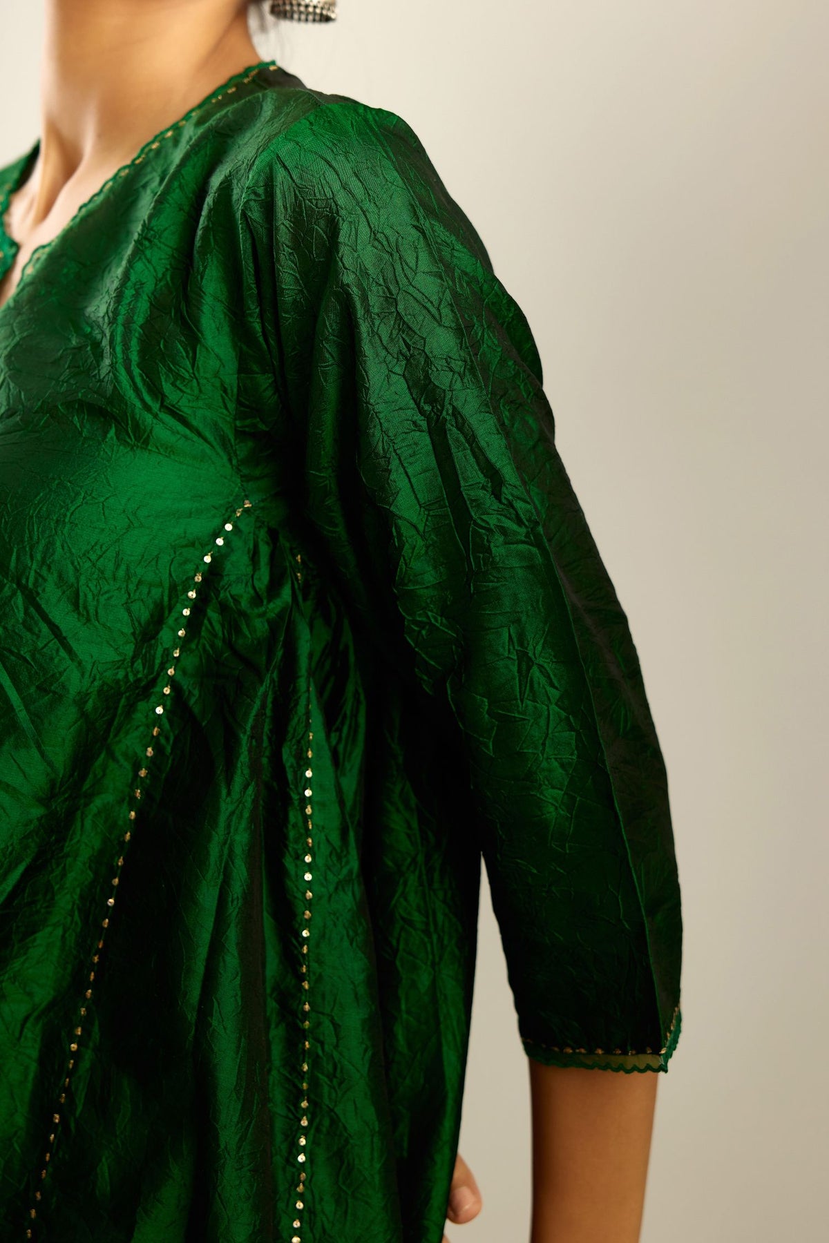 Dark green hand crushed silk kurta set with asymmetric hem, highlighted with gold sequins and embroidered scalloped organza at edges.