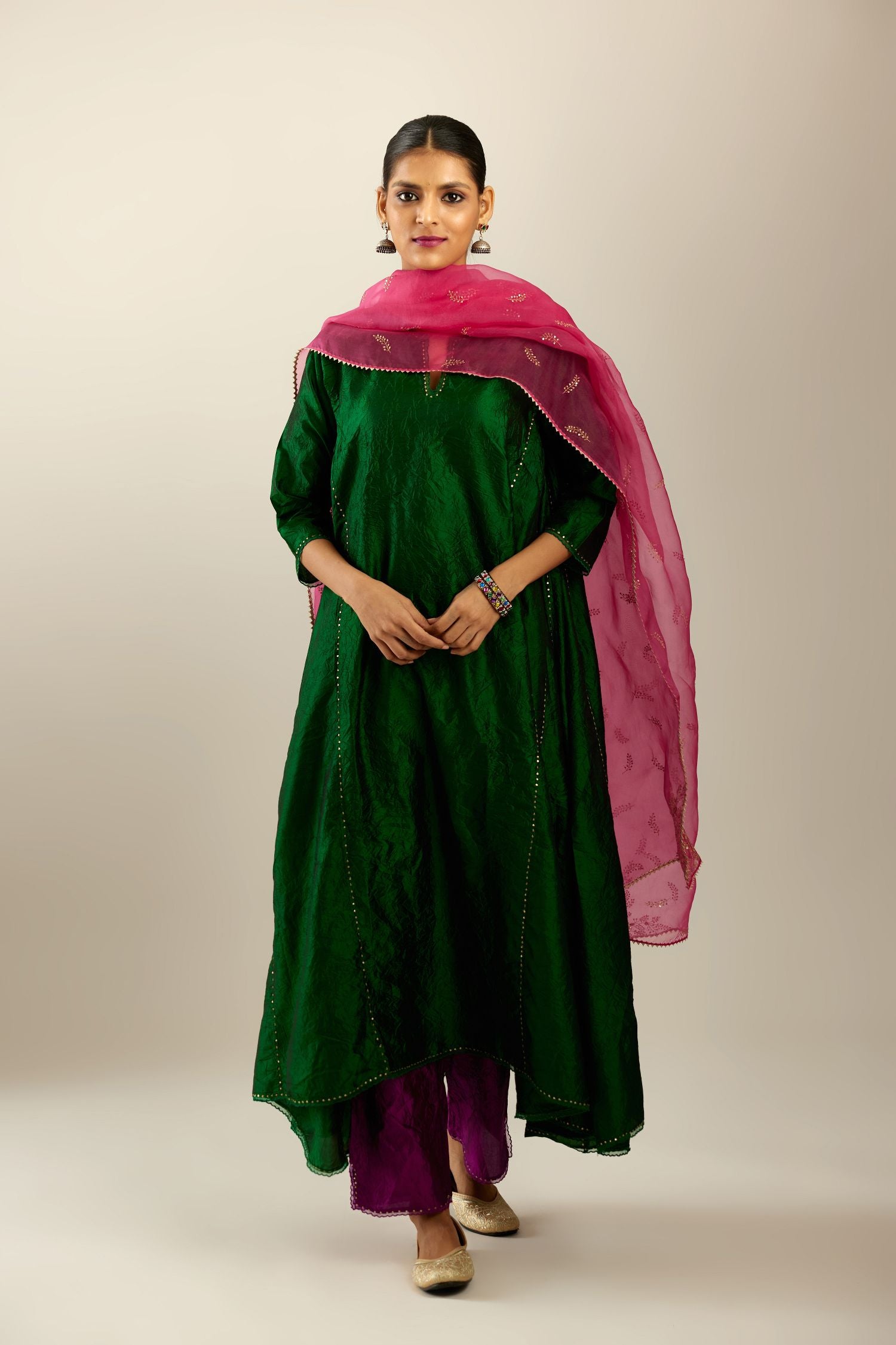 Dark green hand crushed silk kurta set with asymmetric hem, highlighted with gold sequins and embroidered scalloped organza at edges.