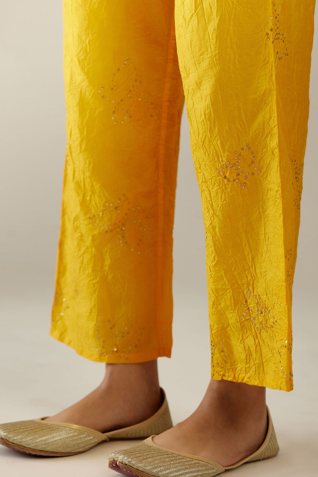 Deep yellow crushed silk pants with side pockets and assorted sequined butterflies till mid-calf length.