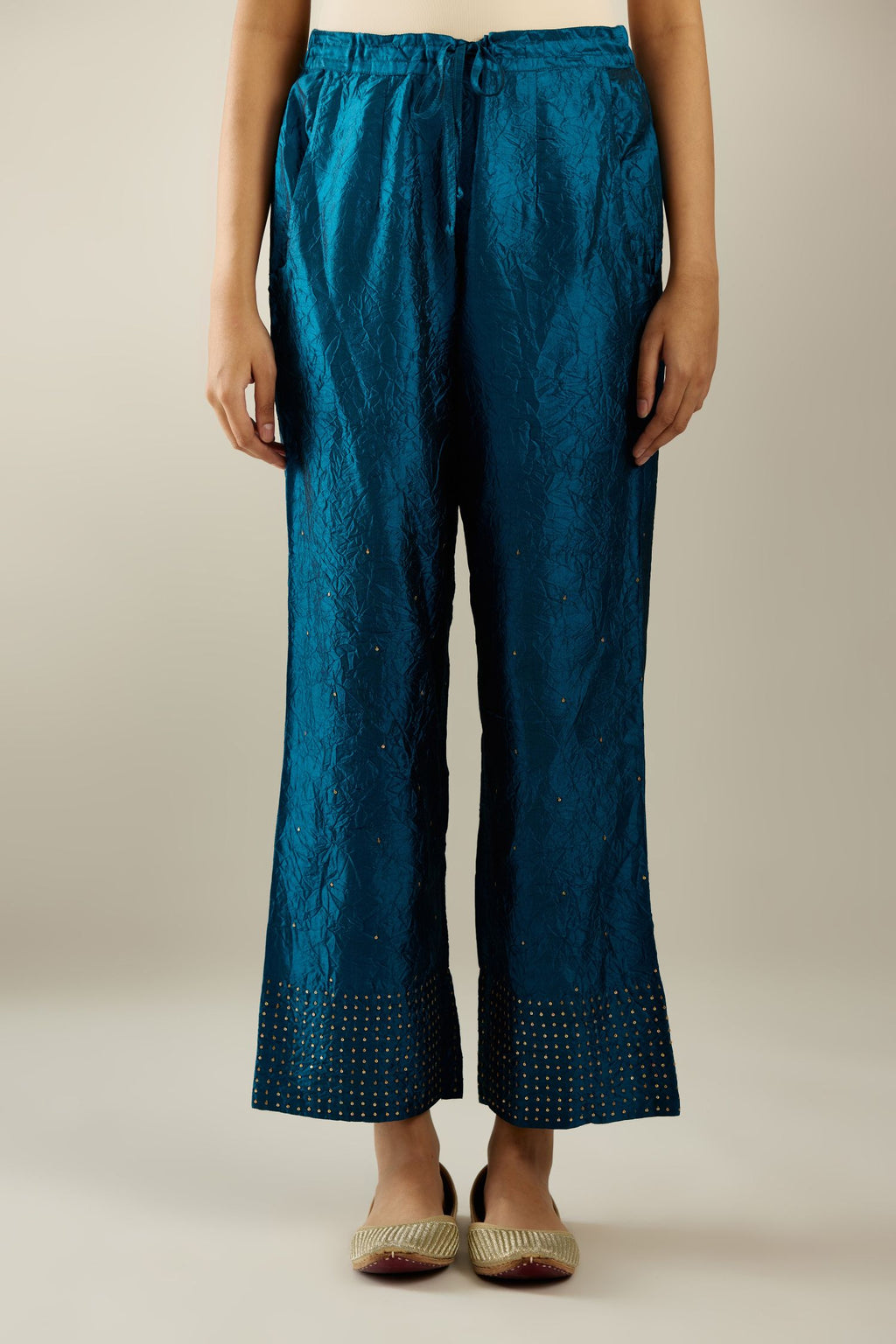 Dark teal hand crushed silk straight pants detailed with gold sequins at hem and a single sequin buti is sprayed all over the pants and side pockets