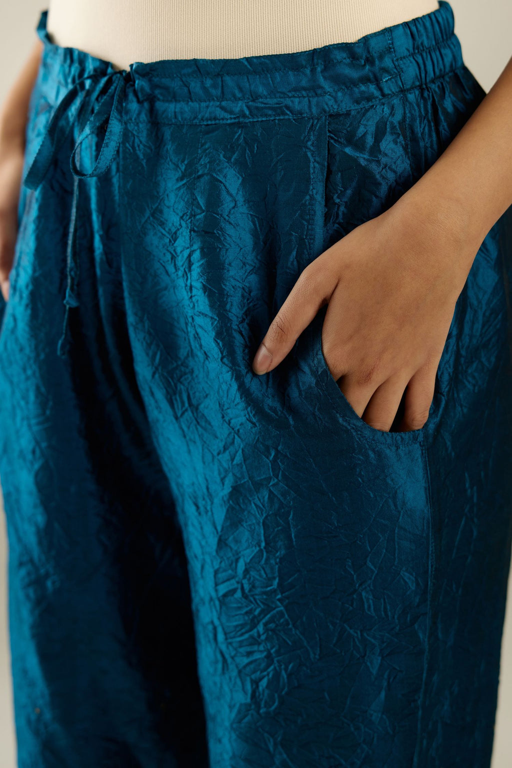 Dark teal hand crushed silk straight pants detailed with gold sequins at hem and a single sequin buti is sprayed all over the pants and side pockets