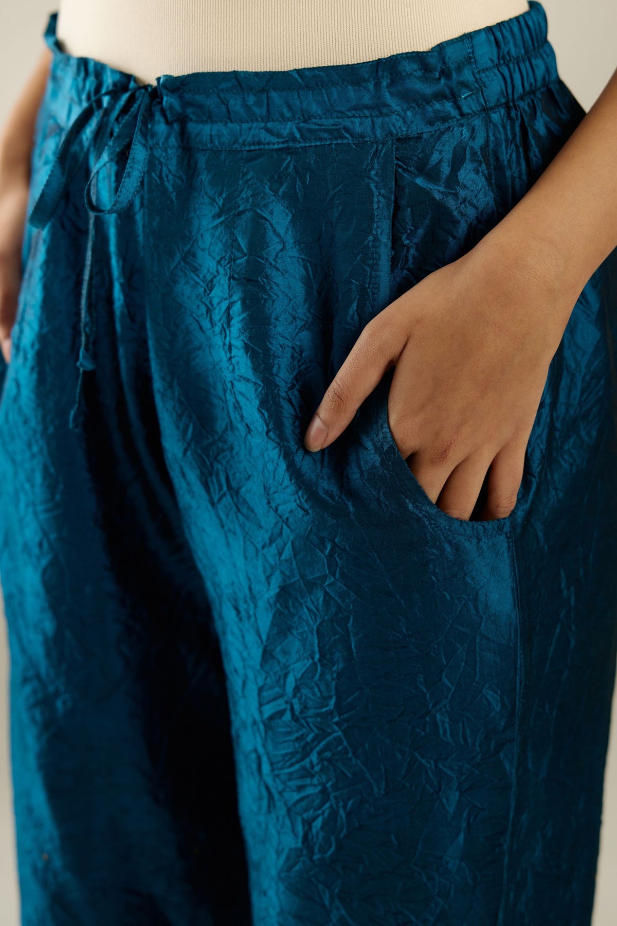 Dark teal hand crushed silk straight pants detailed with gold sequins at hem and a single sequin buti is sprayed all over the pants and side pockets