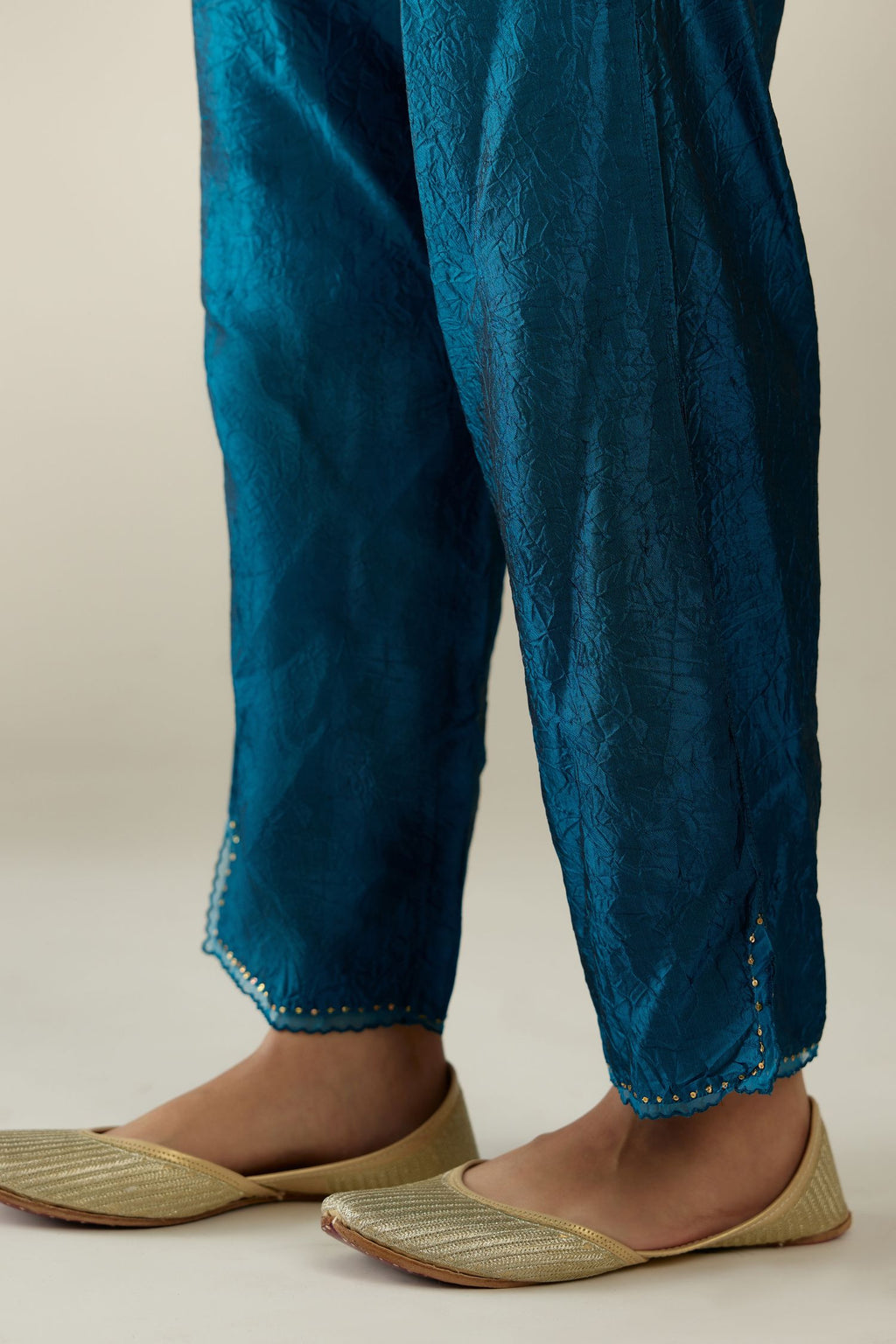 Dark teal hand crushed silk straight pants with scalloped and embroidered organza at edges and detailed with a single line of sequins at hem