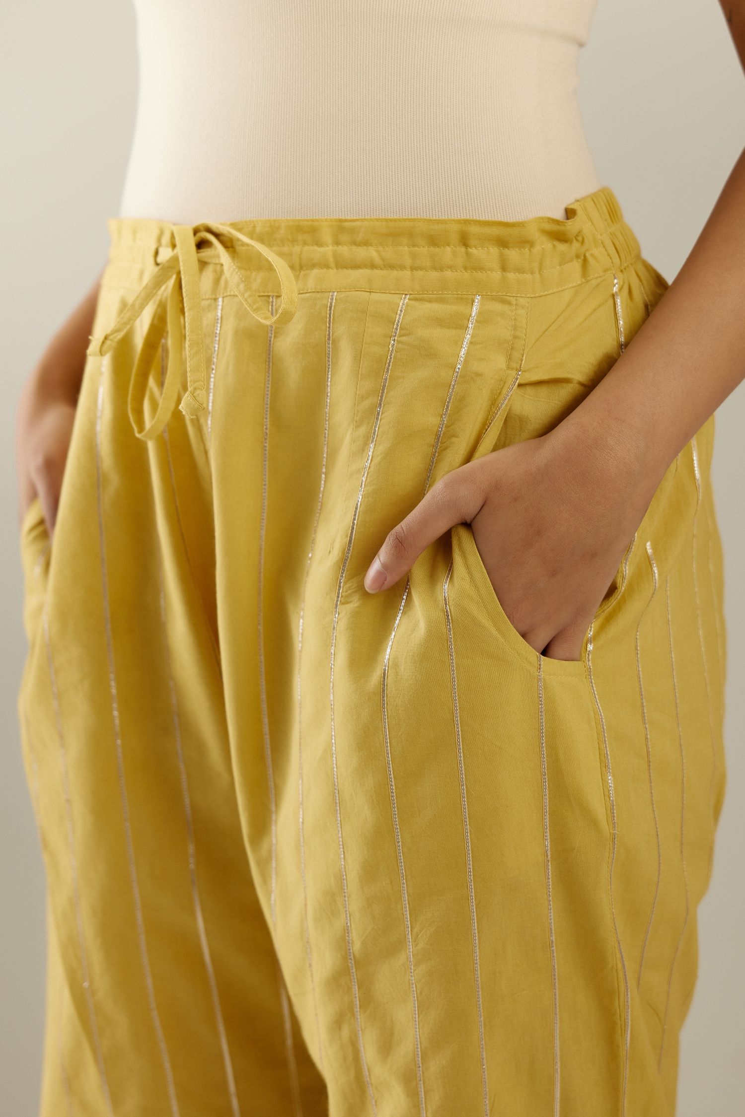 Yellow cotton straight pants with all-over gold gota lines and zari embroidery at hem.