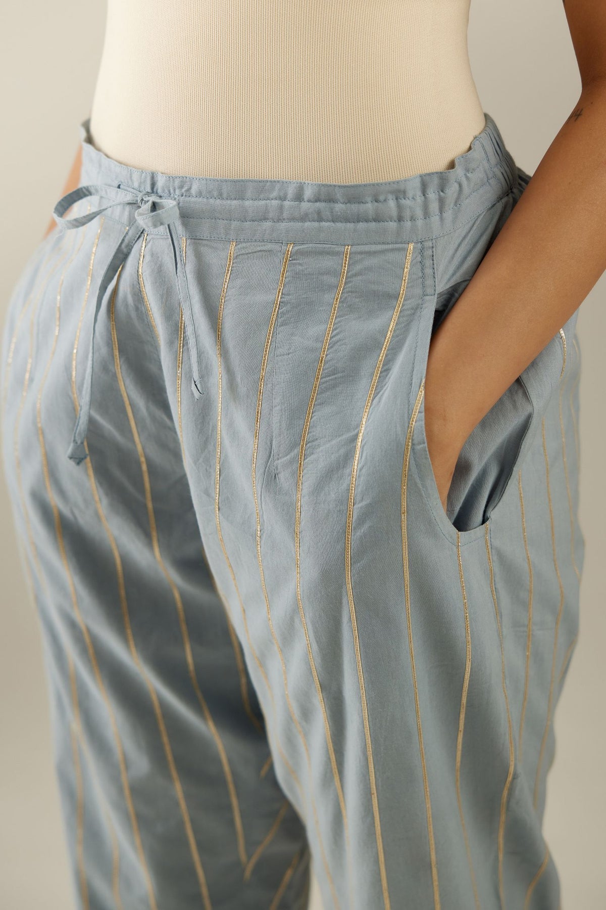 Blue cotton straight pants with all-over gold gota lines and zari embroidery at hem.