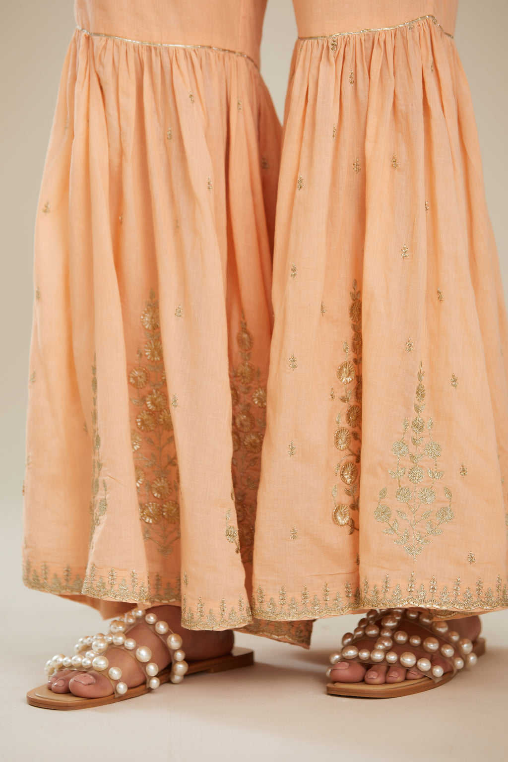 Peach farshi with gold zari and gota embroidery and gota detailing at knee joint seam. (Farshi)