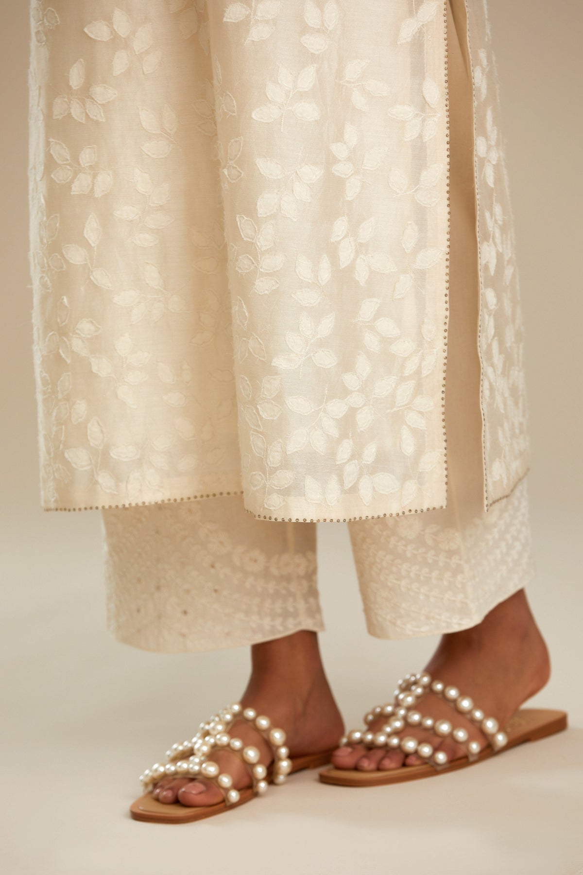Off white silk chanderi straight kurta set with graded leaf appliqué and sequin detail at edges.
