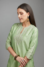 Lime green straight kurta set with silver zari embroidery at neck and scalloped hem