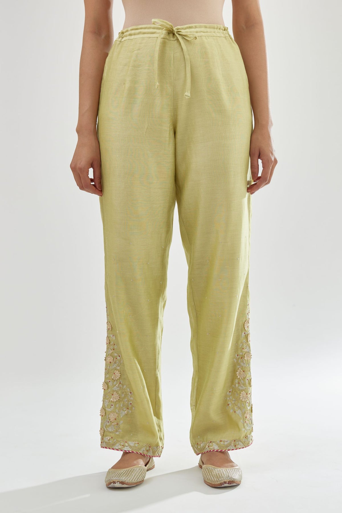 Green silk chanderi straight pants, hem is detailed with zari, dori and gota embroidered boota at sides.
