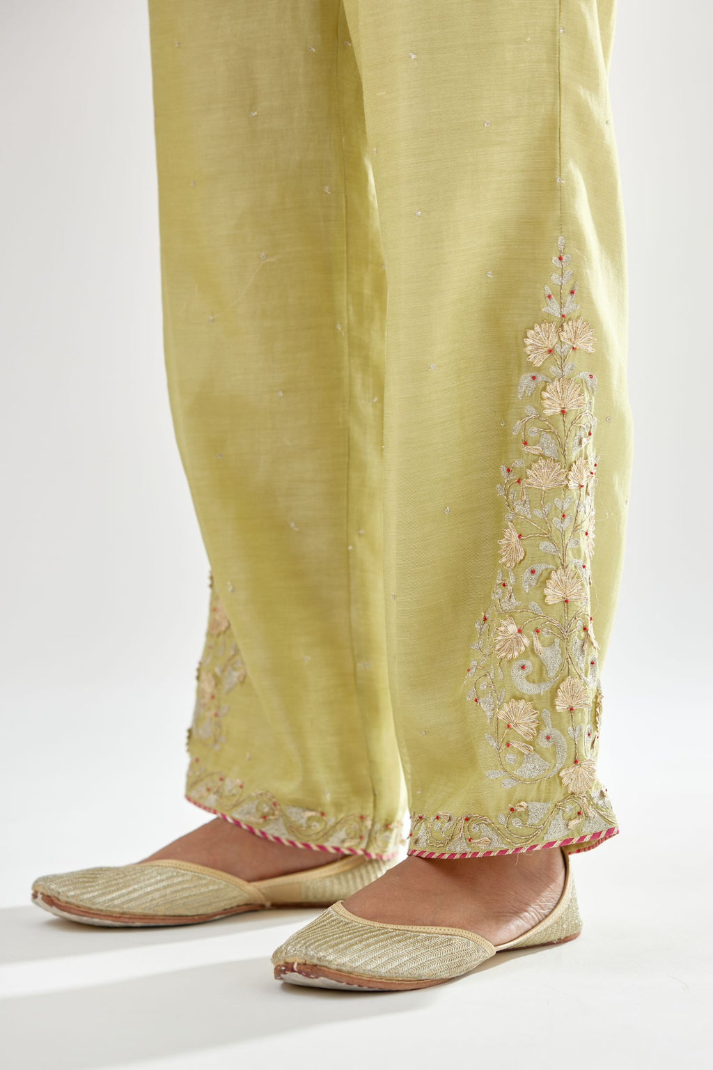 Green silk chanderi straight pants, hem is detailed with zari, dori and gota embroidered boota at sides.