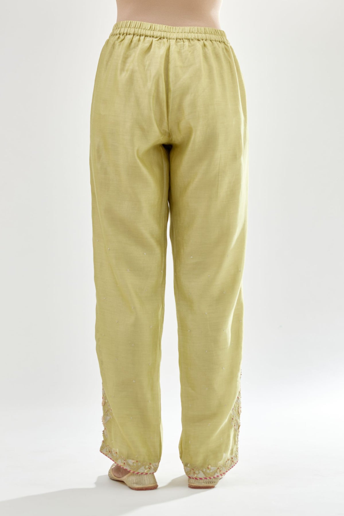 Green silk chanderi straight pants, hem is detailed with zari, dori and gota embroidered boota at sides.