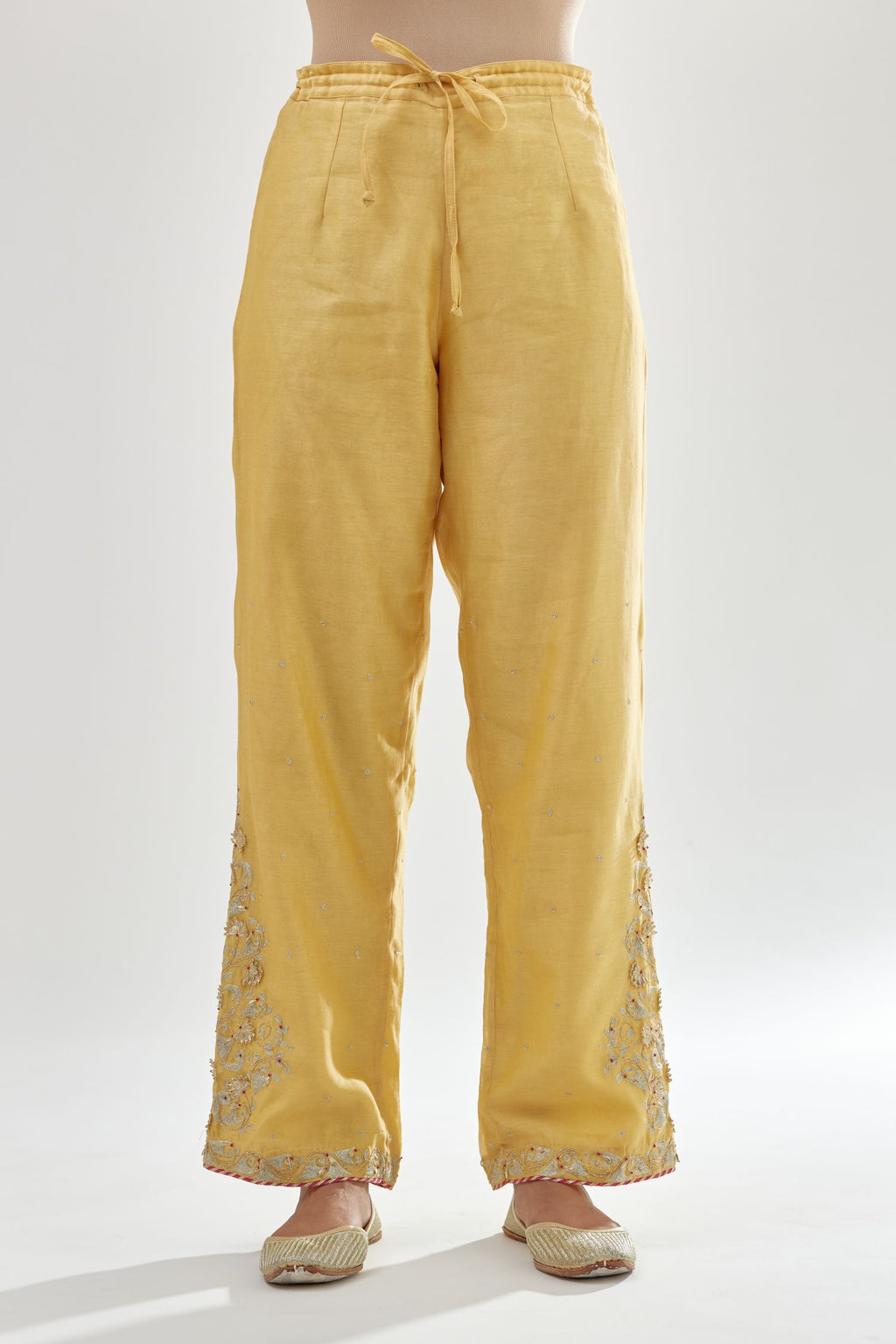 Yellow silk chanderi straight pants, hem is detailed with zari, dori and gota embroidered boota at sides.