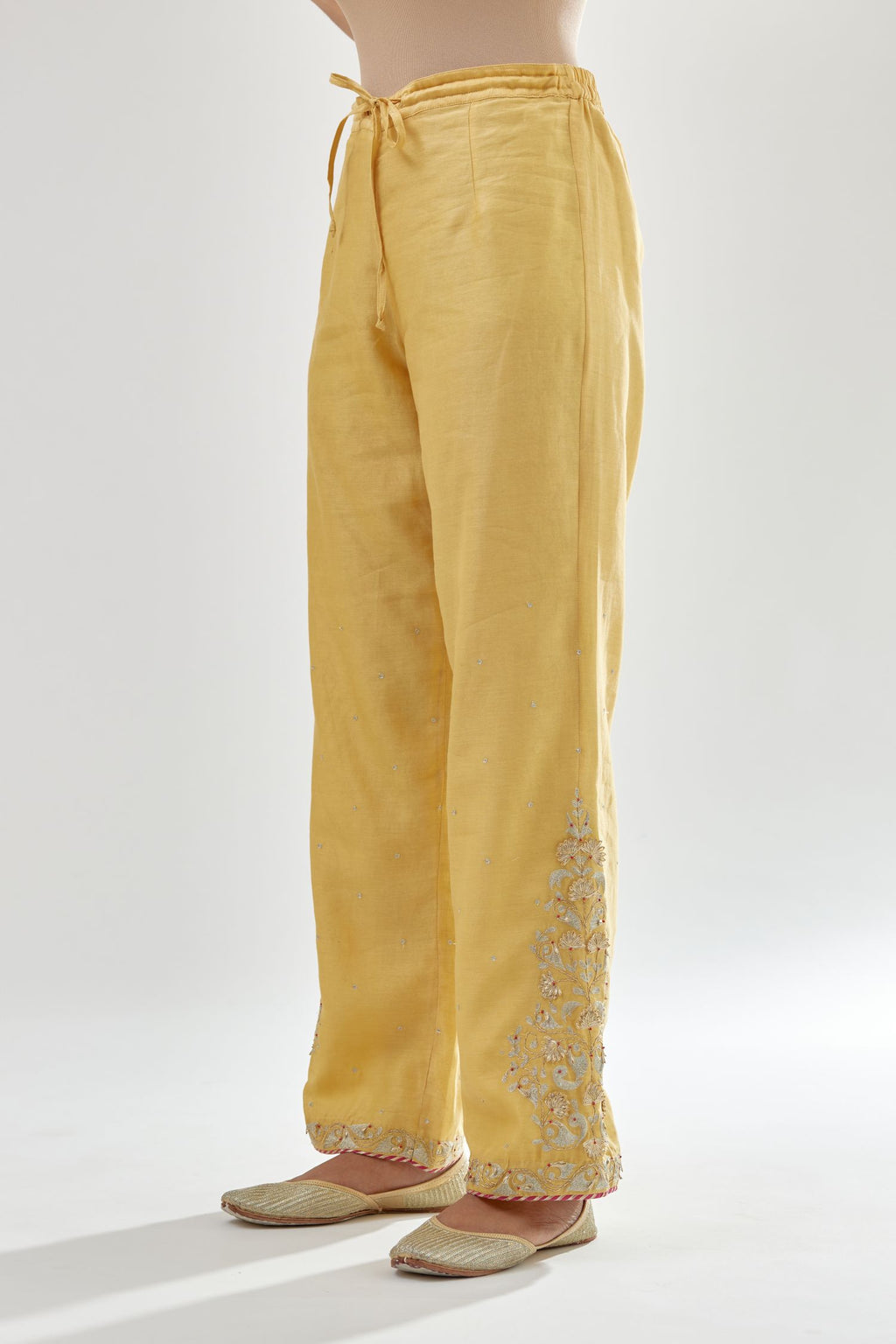 Yellow silk chanderi straight pants, hem is detailed with zari, dori and gota embroidered boota at sides.