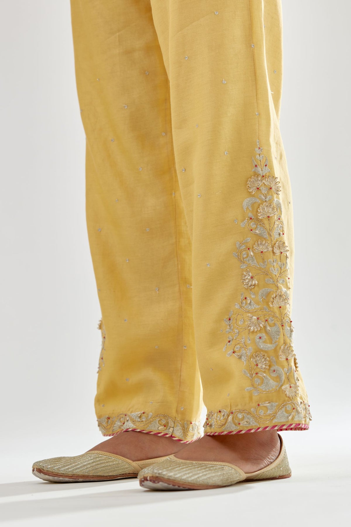 Yellow silk chanderi straight pants, hem is detailed with zari, dori and gota embroidered boota at sides.