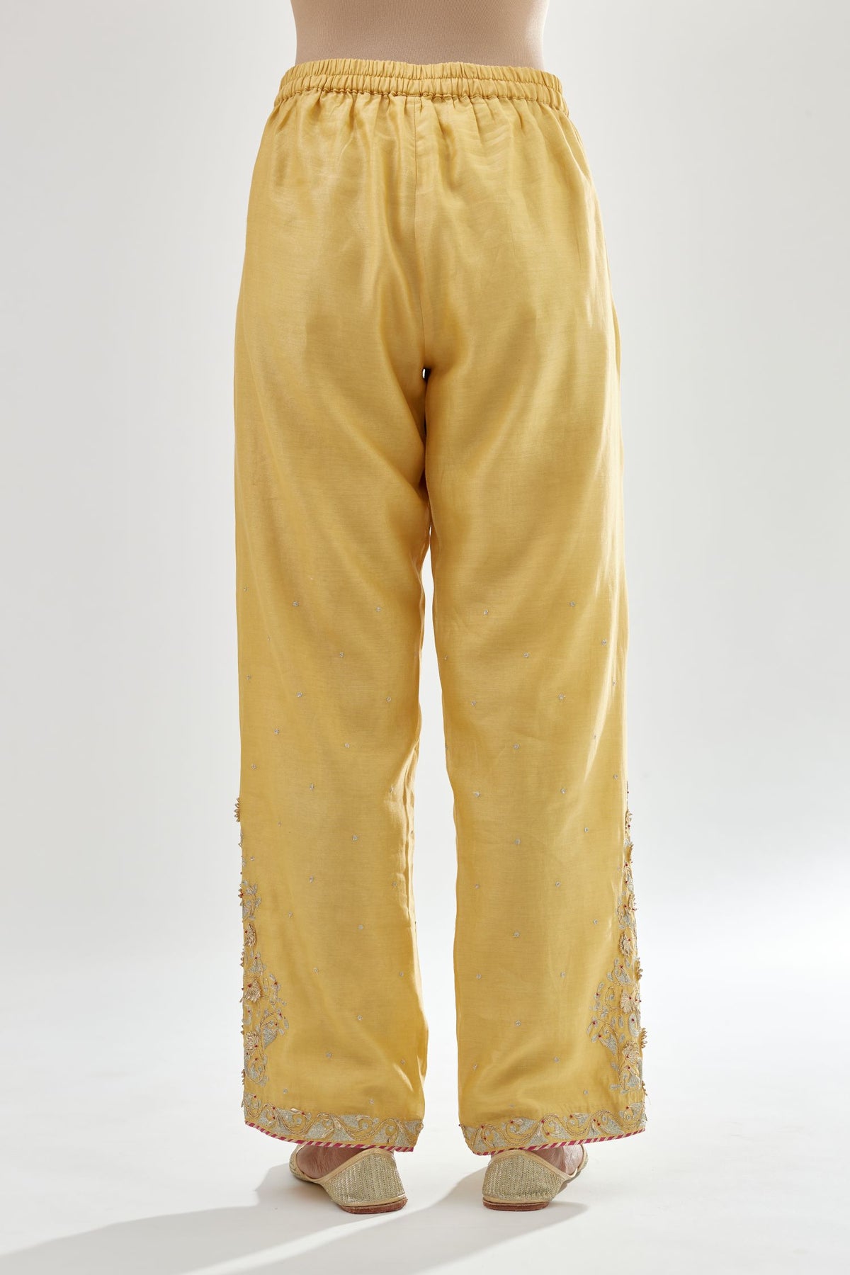 Yellow silk chanderi straight pants, hem is detailed with zari, dori and gota embroidered boota at sides.