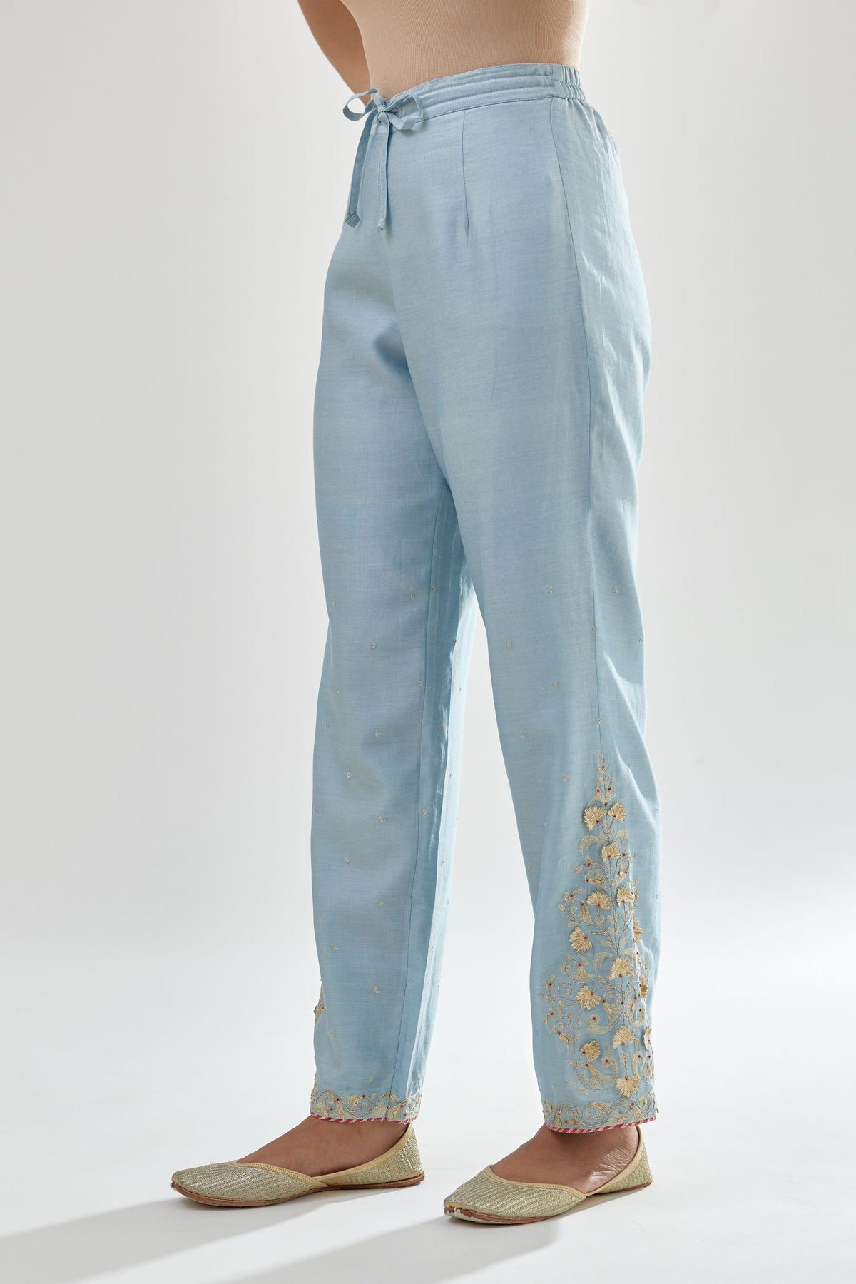 Blue silk chanderi straight pants, hem is detailed with zari, dori and gota embroidered boota at sides.