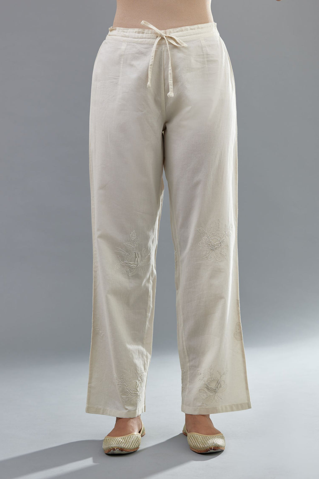 Off white cotton straight pants with all-over applique, highlighted with sequins work.