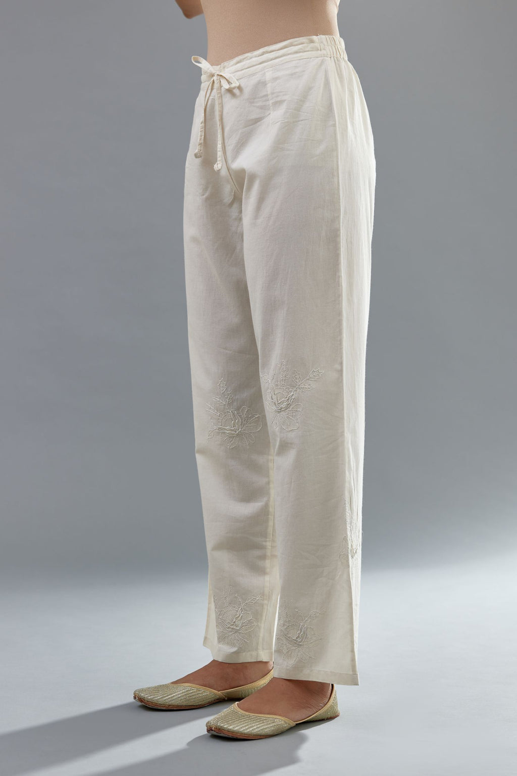Off white cotton straight pants with all-over applique, highlighted with sequins work.