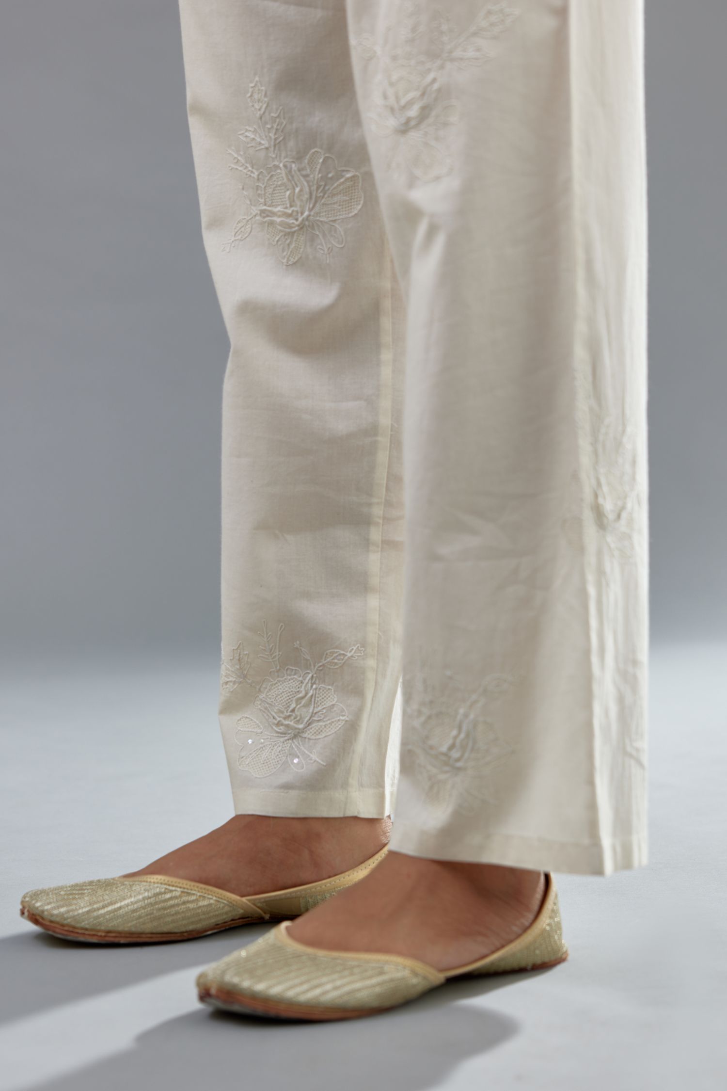 Off white cotton straight pants with all-over applique, highlighted with sequins work.