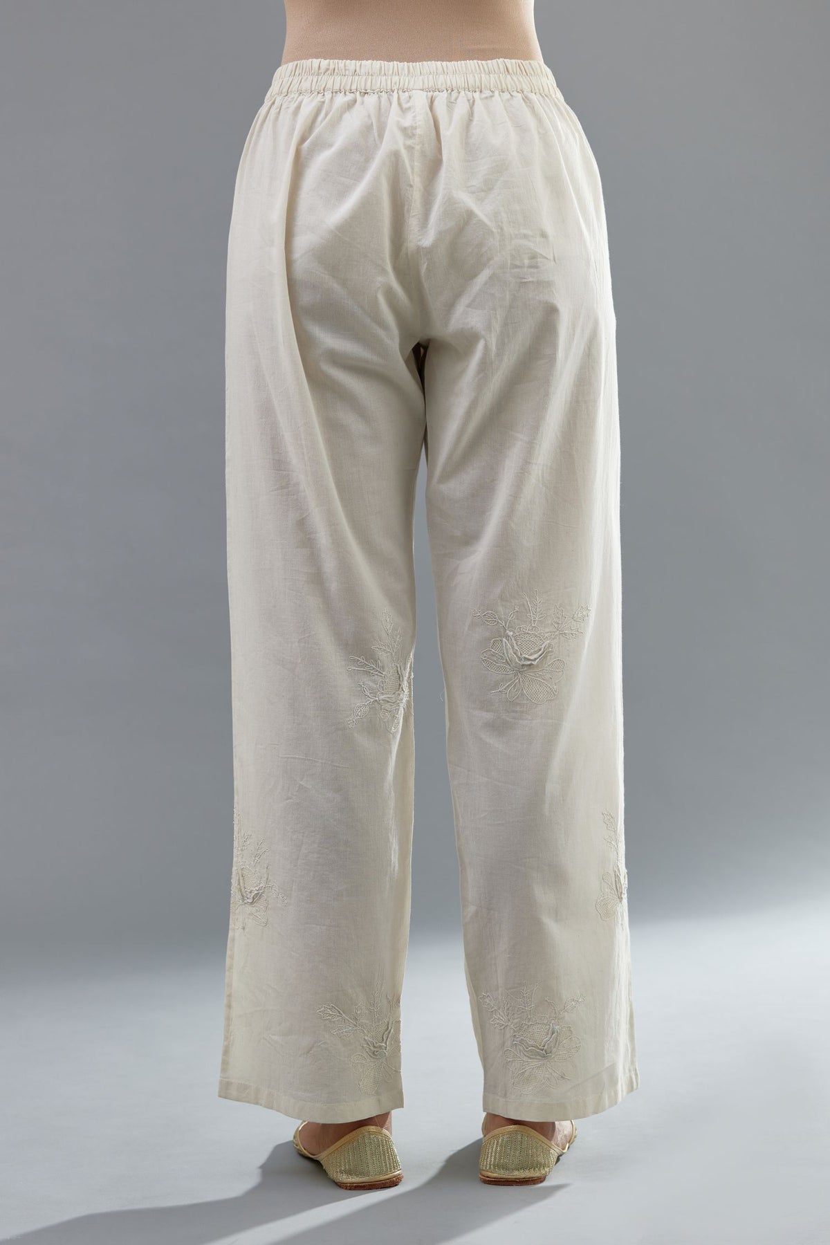 Off white cotton straight pants with all-over applique, highlighted with sequins work.