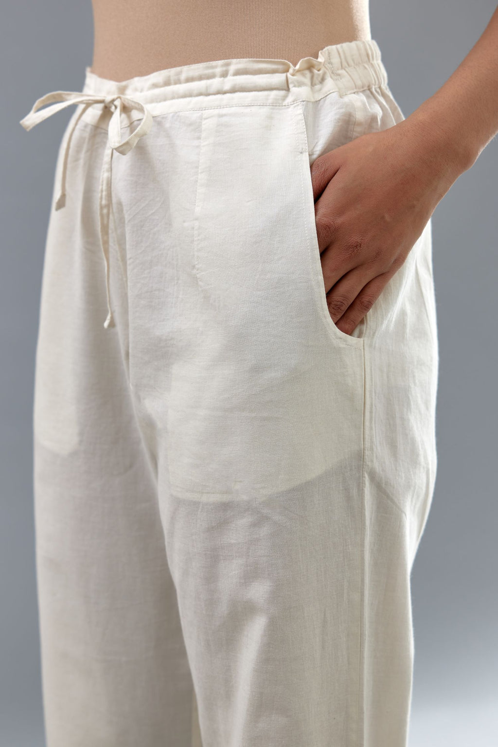 Off white cotton straight pants with appliqué and dori embroidery work at bottom hem.