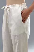 Off white cotton straight pants with appliqué and dori embroidery work at bottom hem.