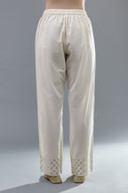 Off white cotton straight pants with appliqué and dori embroidery work at bottom hem.