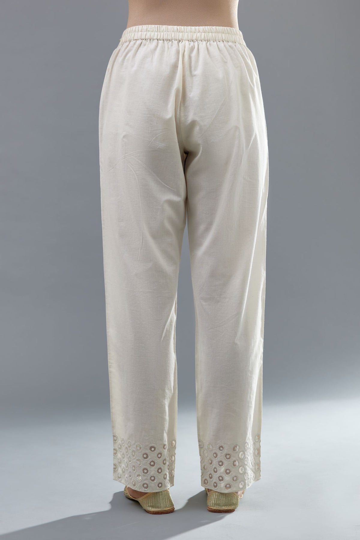 Off white cotton straight pants with appliqué and dori embroidery work at bottom hem.