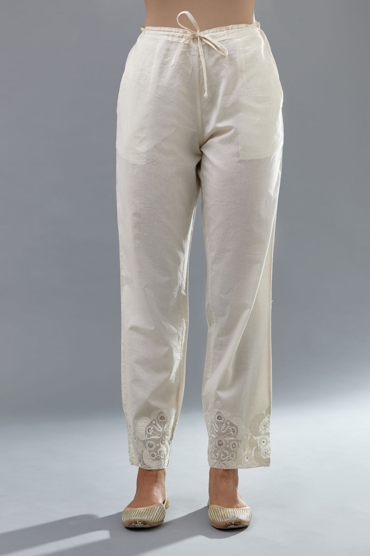 Off white cotton straight pants with appliqué and hand attached sequins detailing at bottom hem.