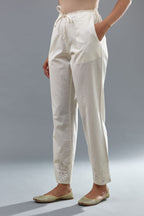 Off white cotton straight pants with appliqué and hand attached sequins detailing at bottom hem.