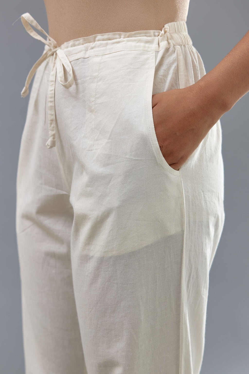 Off white cotton straight pants with appliqué and hand attached sequins detailing at bottom hem.