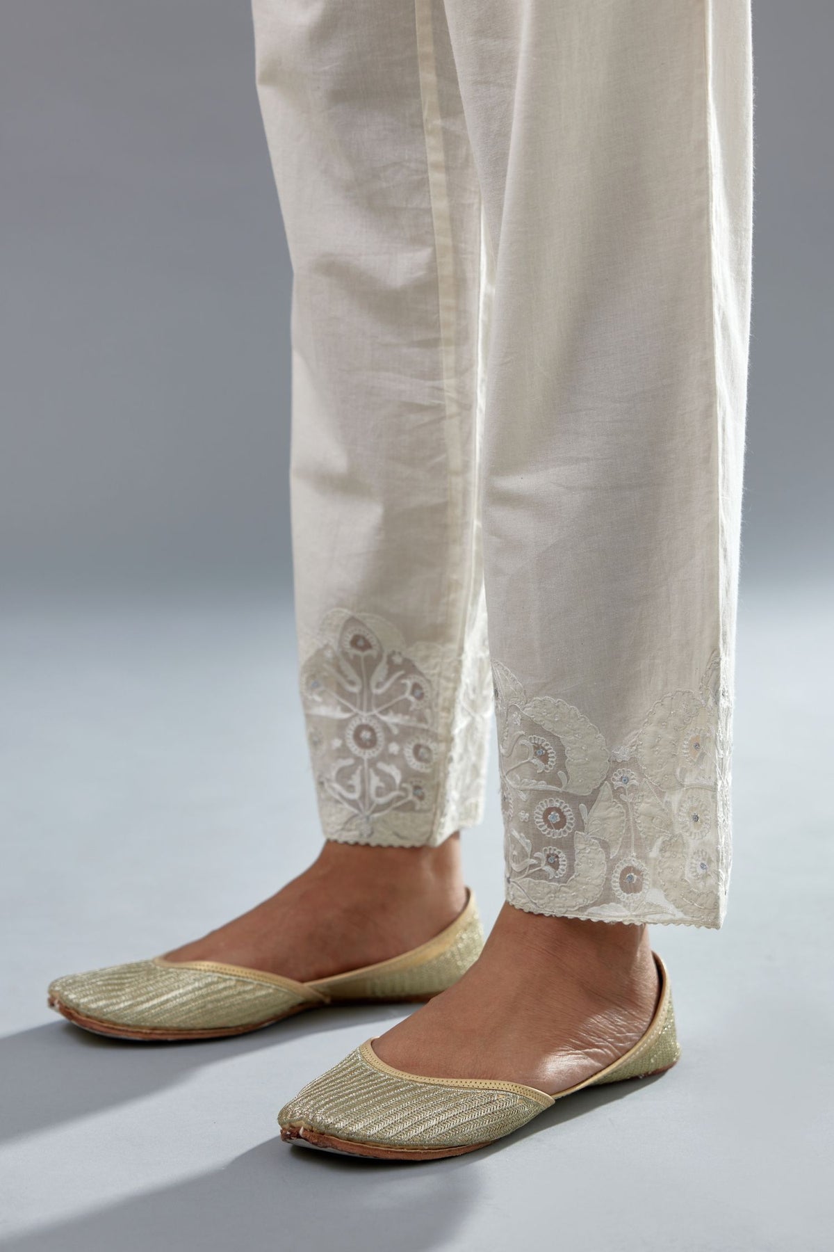 Off white cotton straight pants with appliqué and hand attached sequins detailing at bottom hem.
