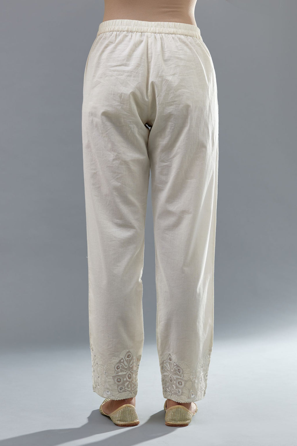 Off white cotton straight pants with appliqué and hand attached sequins detailing at bottom hem.