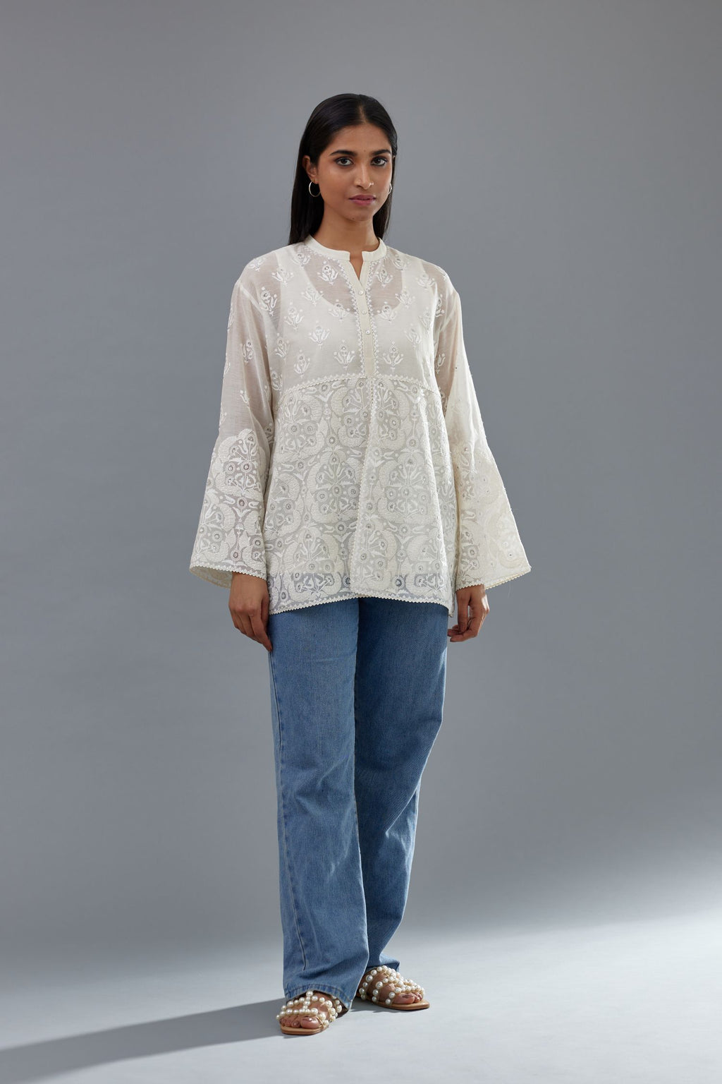 Off white cotton chanderi short top with heavy appliqué, highlighted with sequins, paired with off white cotton straight pants with appliqué and hand attached sequins detailing at bottom hem.