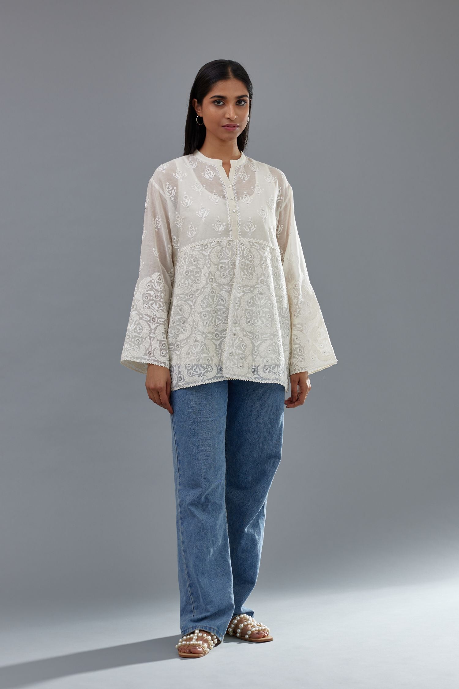 Off white cotton chanderi short top with heavy appliqué, highlighted with sequins, paired with off white cotton straight pants with appliqué and hand attached sequins detailing at bottom hem.
