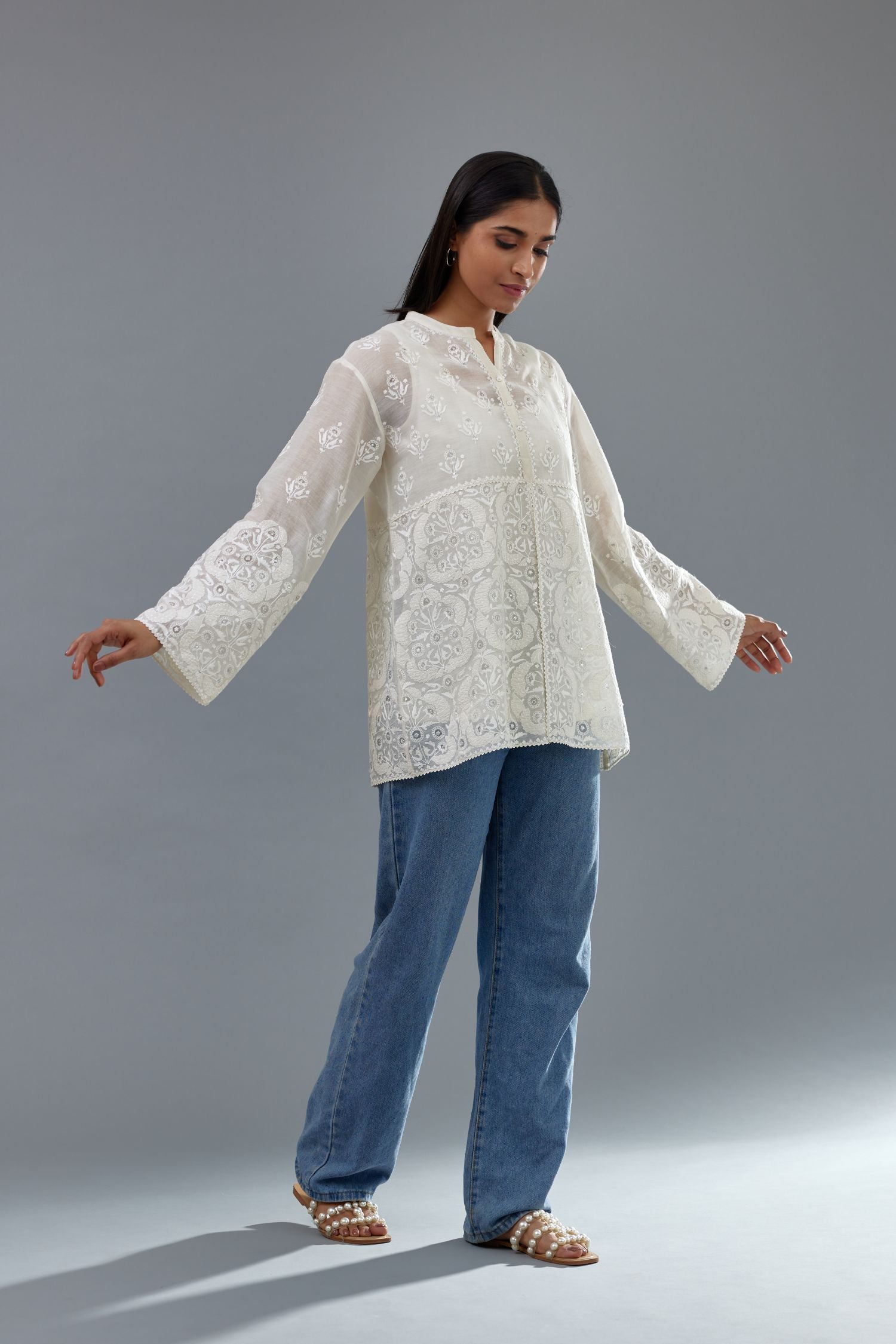 Off white cotton chanderi short top with heavy appliqué, highlighted with sequins, paired with off white cotton straight pants with appliqué and hand attached sequins detailing at bottom hem.