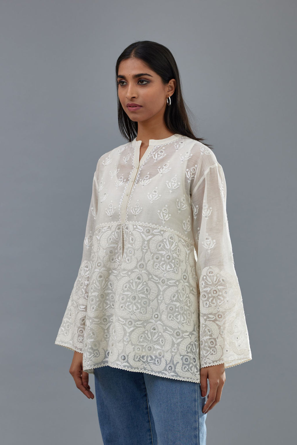 Off white cotton chanderi short top with heavy appliqué, highlighted with sequins, paired with off white cotton straight pants with appliqué and hand attached sequins detailing at bottom hem.