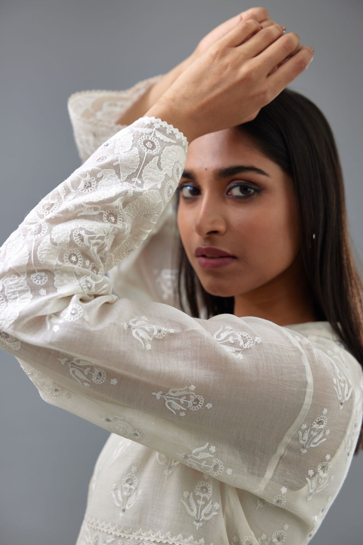 Off white cotton chanderi short top with heavy appliqué, highlighted with sequins, paired with off white cotton straight pants with appliqué and hand attached sequins detailing at bottom hem.