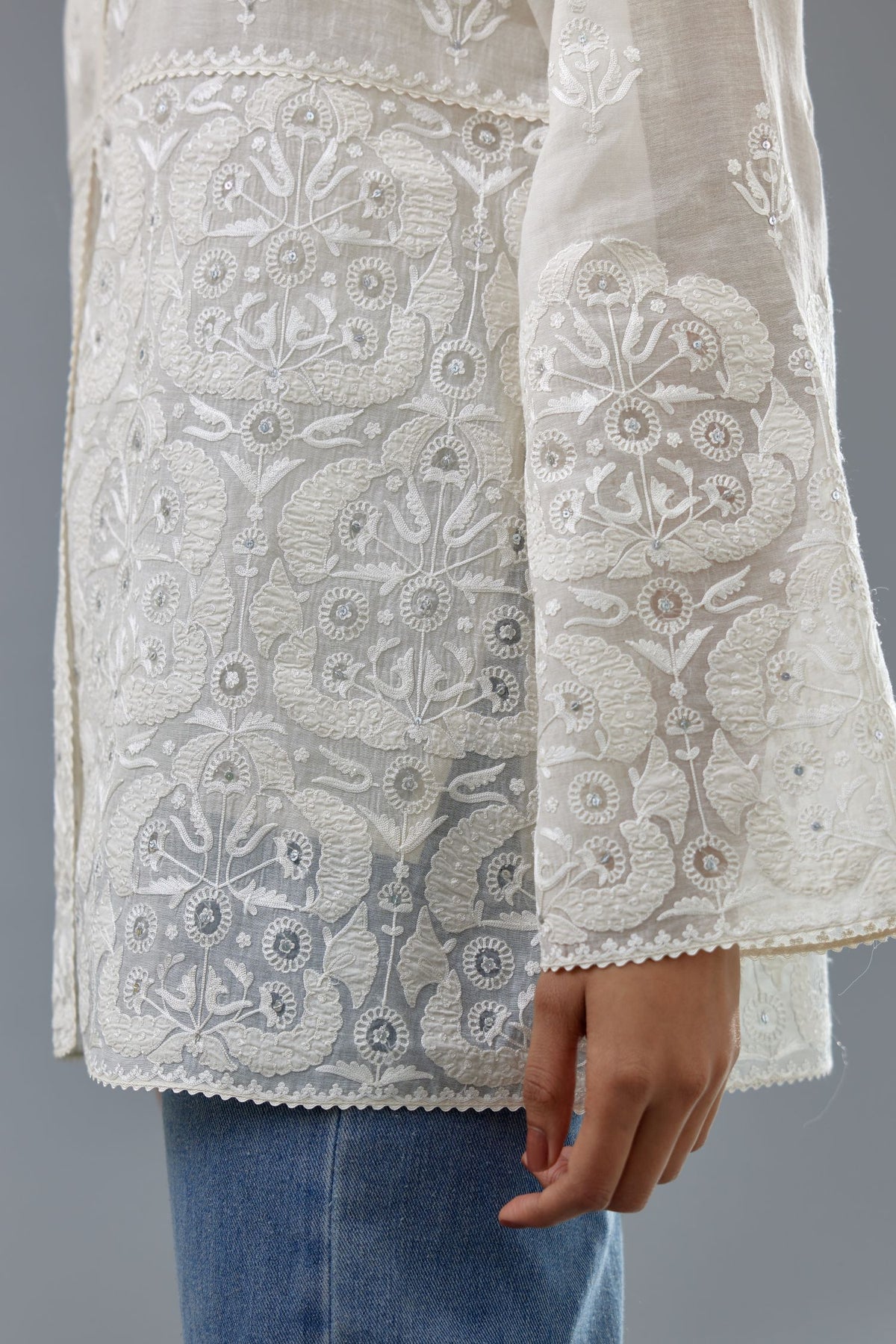 Off white cotton chanderi short top with heavy appliqué, highlighted with sequins, paired with off white cotton straight pants with appliqué and hand attached sequins detailing at bottom hem.