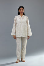 Off white cotton chanderi short top with heavy appliqué, highlighted with sequins, paired with off white cotton straight pants with appliqué and hand attached sequins detailing at bottom hem.