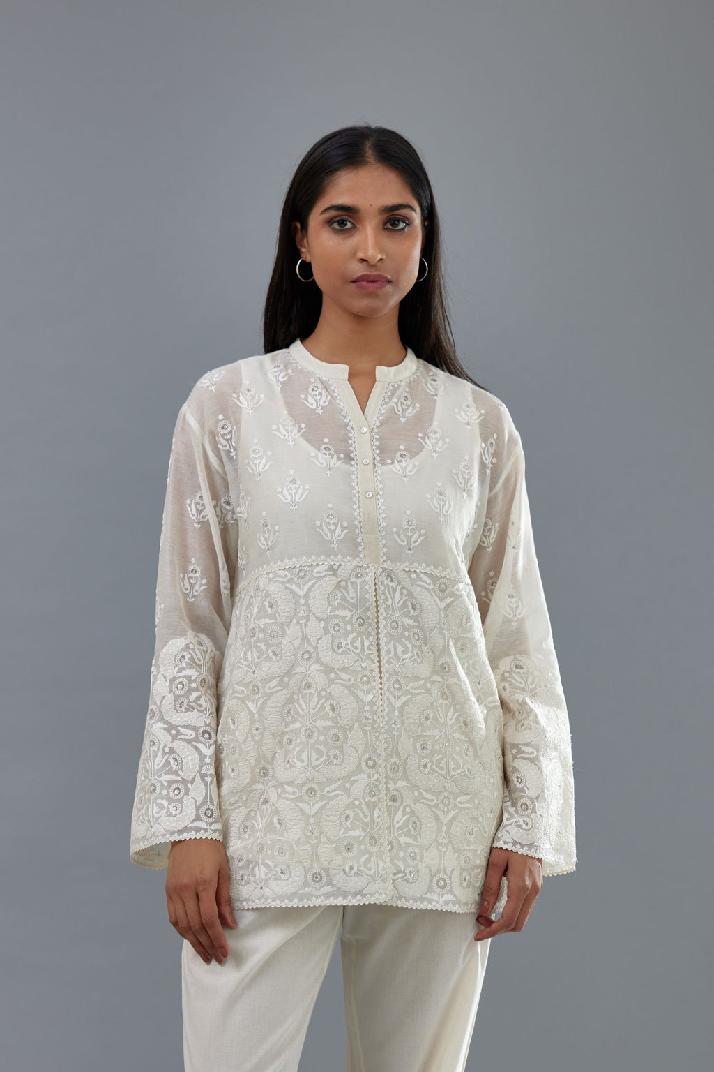 Off white cotton chanderi short top with heavy appliqué, highlighted with sequins, paired with off white cotton straight pants with appliqué and hand attached sequins detailing at bottom hem.