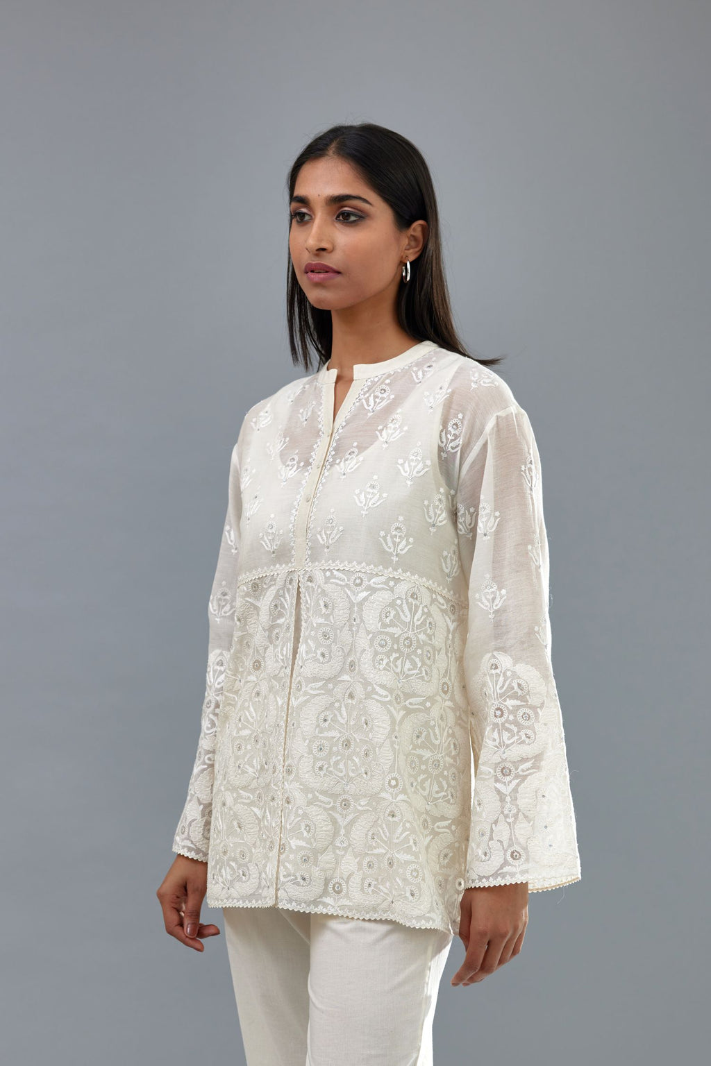 Off white cotton chanderi short top with heavy appliqué, highlighted with sequins, paired with off white cotton straight pants with appliqué and hand attached sequins detailing at bottom hem.