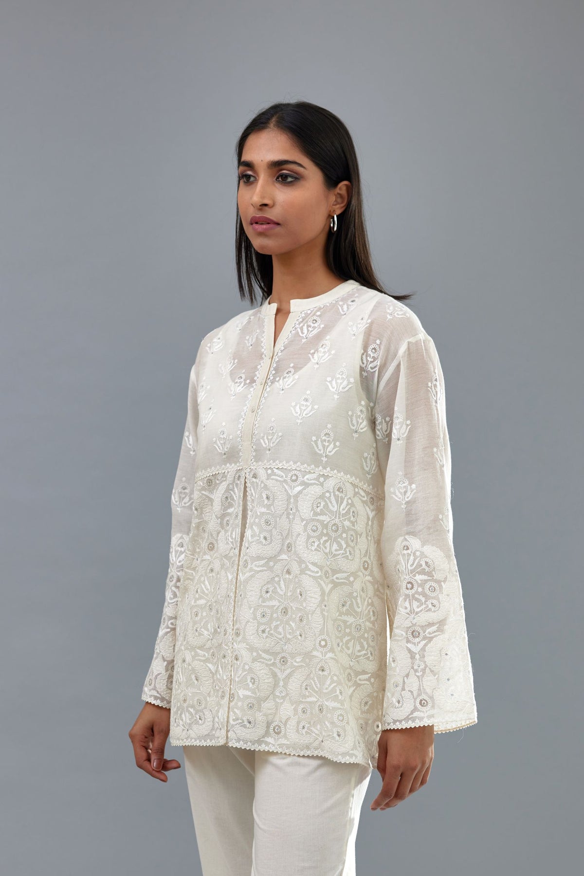 Off white cotton chanderi short top with heavy appliqué, highlighted with sequins, paired with off white cotton straight pants with appliqué and hand attached sequins detailing at bottom hem.
