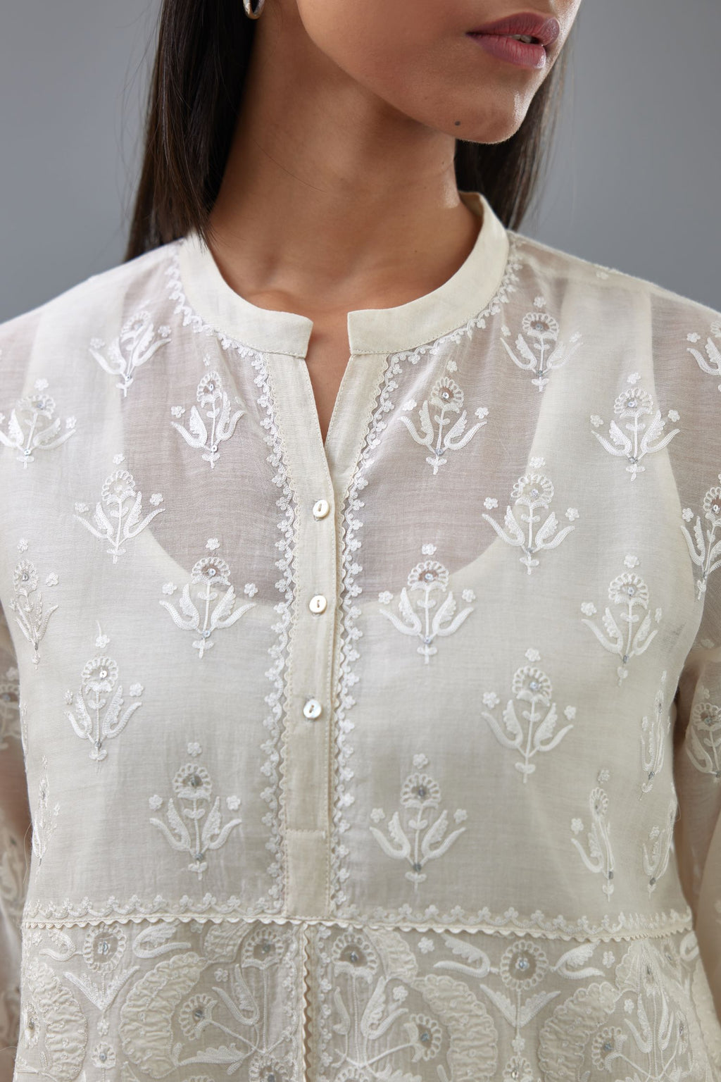 Off white cotton chanderi short top with heavy appliqué, highlighted with sequins, paired with off white cotton straight pants with appliqué and hand attached sequins detailing at bottom hem.